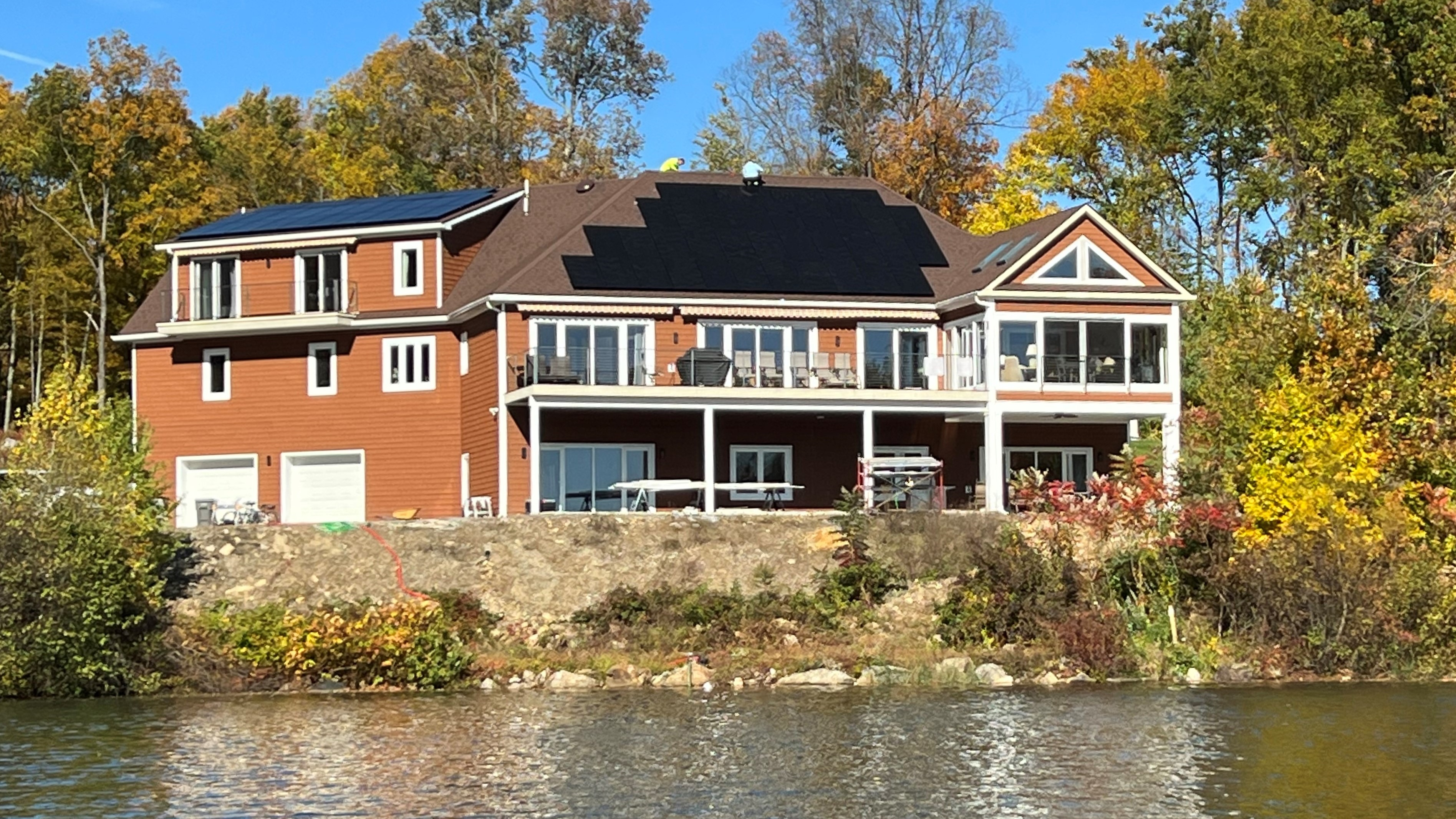 Completed construction of a home built with ICF. The home has solar panels on the roof and overlooks a body of water.
